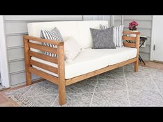 a white couch sitting on top of a rug next to a wooden chair and table