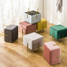 four different colored stools sitting on top of a hard wood floor next to a window