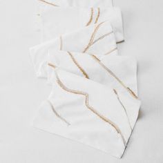 three white napkins with gold thread on them