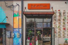 the outside of a flower shop with lots of flowers hanging on the side of it