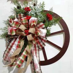 a christmas wreath on top of a wagon wheel with holly and candy canes attached to it