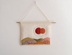 a white wall hanging with an orange and pink patchwork design on it's side