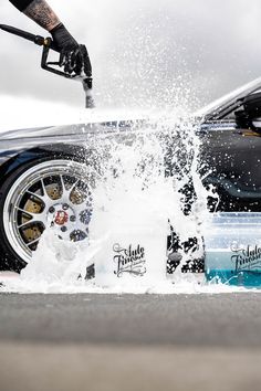 a man is spraying water on his car's wheels