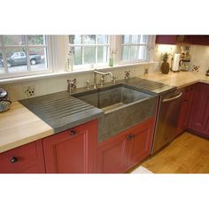 a kitchen with red cabinets and stainless steel sink in the center, along with wooden counter tops