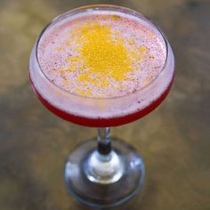 a close up of a drink in a wine glass with yellow sprinkles