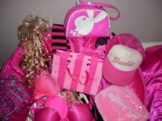 a barbie doll is laying on the bed with her pink gift bag and other items