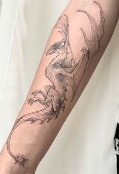 a man's arm with a dragon tattoo on the left side of his arm