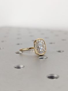 a diamond ring sitting on top of a metal surface with drops of water around it