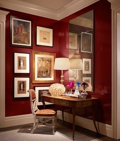 a room with red walls and pictures on the wall, including a desk in front of a chair