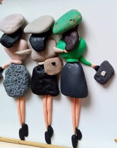 three little figurines are standing next to each other with rocks on their backs