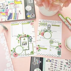 the contents of a planner spread out on a pink surface with flowers and pens nearby