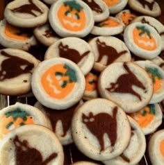 decorated cookies are on a cooling rack with orange and white frosting in the shape of cats