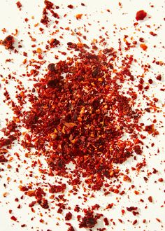 a pile of red chili flakes sitting on top of a white table