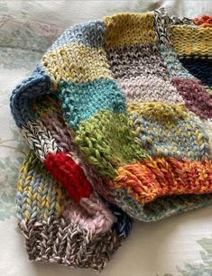 four knitted dishcloths are laying on the bed together, one is multicolored