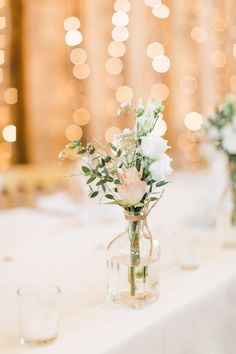 flowers are in vases on the table at a wedding reception with boket lights behind them