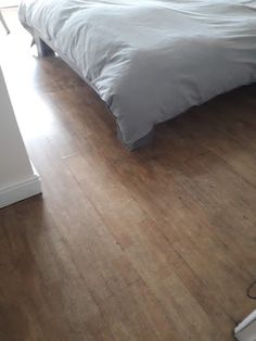 a bed sitting on top of a wooden floor next to a window