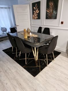 a dining room table with black chairs and gold accents