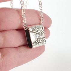 a hand holding a small silver and black necklace