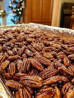 there is a tray full of pecans on the table in front of a christmas tree