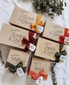 four brown boxes with red, yellow and green bows on them sitting on a table