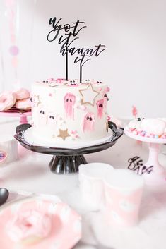 a white cake with pink icing and stars on top is sitting on a table