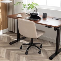 a desk with a laptop on it in front of a window and potted plant