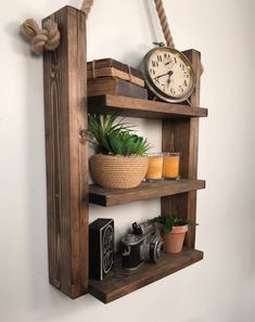 a wooden shelf with a clock, plant and other items on it next to a wall