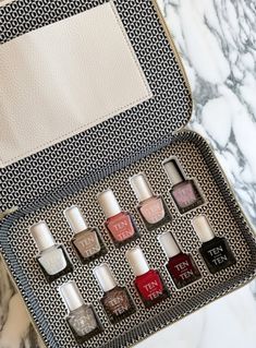 an open travel case filled with nail polishes on top of a marble countertop