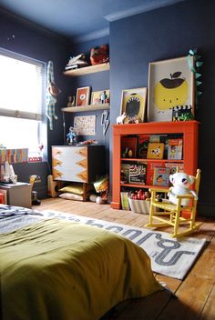 a child's bedroom with blue walls and orange furniture, including a yellow rocking chair