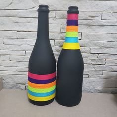 two black vases with multicolored ribbons on them sitting in front of a brick wall