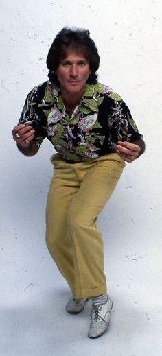 a woman in yellow pants is posing for the camera with her hands on her hips