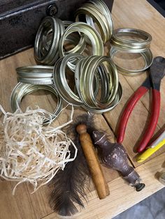 some metal items are sitting on a wooden table with pliers and other tools around them