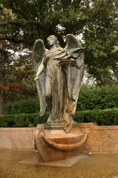 an angel statue sitting on top of a fountain