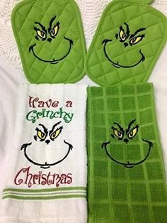 three green kitchen towels with embroidered grin face on them, one has the words have a gracy christmas written on it