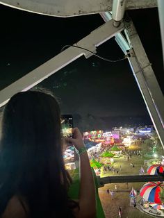 a woman taking a photo of the fairground at night