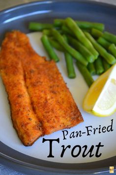 fish, asparagus and lemon on a plate with the words pan - fried trout