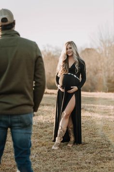 a pregnant woman in a black dress and cowboy boots is standing next to a man