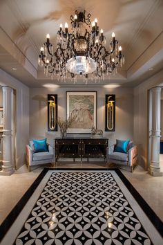 a fancy living room with chandelier and two blue chairs in front of it