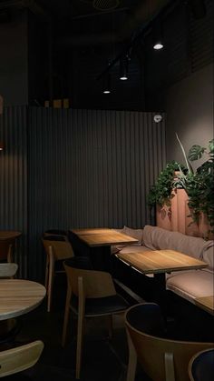 an empty restaurant with tables and chairs in front of a wall that has plants growing on it