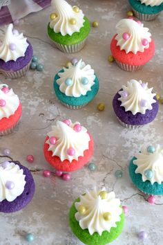 cupcakes decorated with white frosting and colorful icing on a marble surface