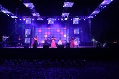 a group of people standing on top of a stage with lights in the dark behind them