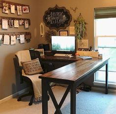 a desk with a computer on top of it in front of a window filled with pictures