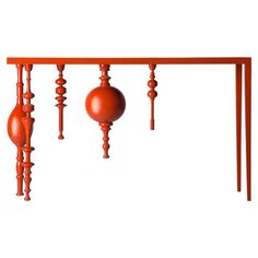 an orange table with three red balls hanging from it's sides and two wooden poles