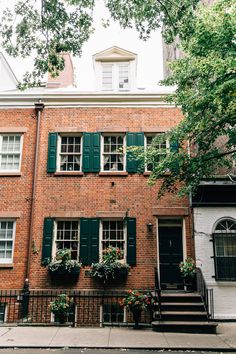 an old brick building with green shutters and flowers on the front steps in new york city