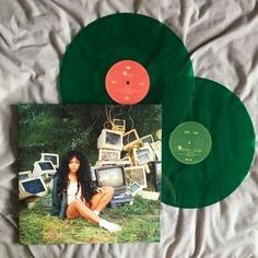 a green vinyl record sitting on top of a bed next to a pile of old televisions