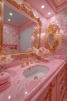 a pink bathroom with gold accents and mirrors