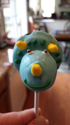 a close up of a person holding a cake on a stick with yellow and green decorations