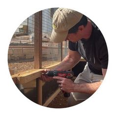 a man is using a drill to attach a bird in a cage on the ground