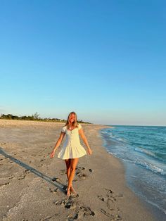 a woman is walking on the beach with footprints in the sand