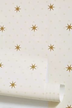 a white wall with gold stars on it next to a roll of tape and scissors